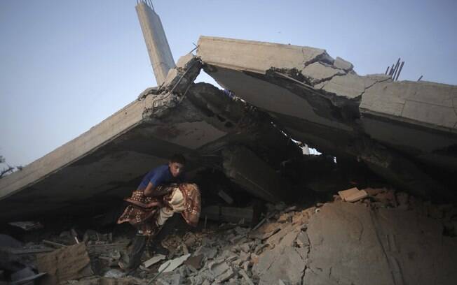 Palestinos tentam salvar o que podem de seus pertences de destroços de casa destruída por ataque de Israel em Gaza (8/7)