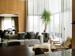 Madeira e pé direito alto dão elegãncia para apartamento de homem mais velho