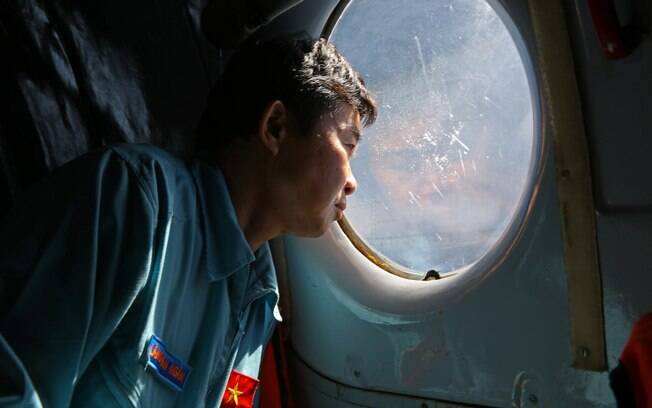 Oficial das Forças Armadas do Vietnã olha pela janela durante buscas pelo voo desaparecido da Malaysia Airlines (14/3). Foto: AP