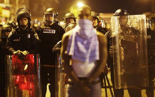 Ativista em frente de linha policial da tropa de choque desafia toque de recolher em Baltimore, EUA (28/04)