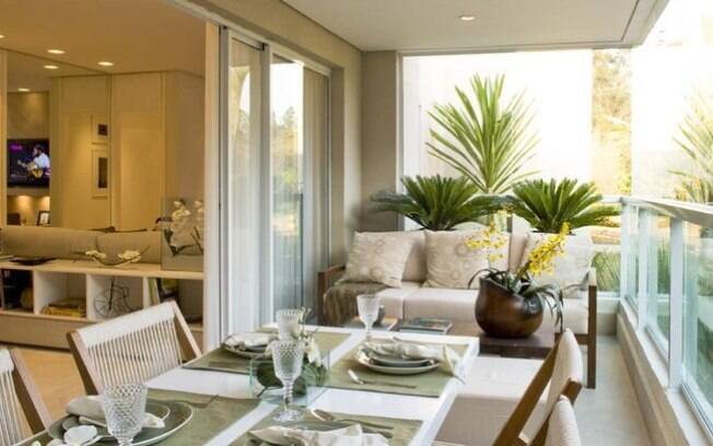 Ganhe mais espaço na sala ao levar a mesa de jantar para a varanda fechada. No apartamento acima, a porta de correr faz a integração entre os ambientes