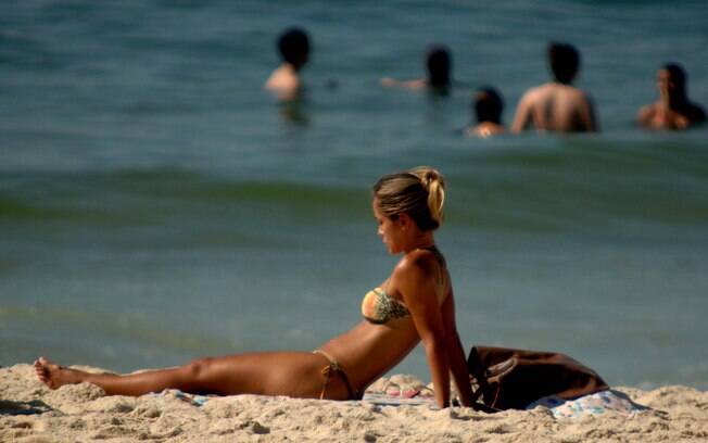 Mulher toma banho de sol nesta quinta-feira (23) na capital fluminense