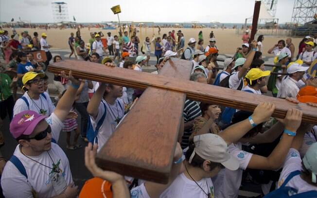 Jovens carregam cruz símbolo da JMJ na praia de Copacabana no domingo (21). Ela foi entregue aos jovens pelo Papa João Paulo II, na edição de 1983 do evento