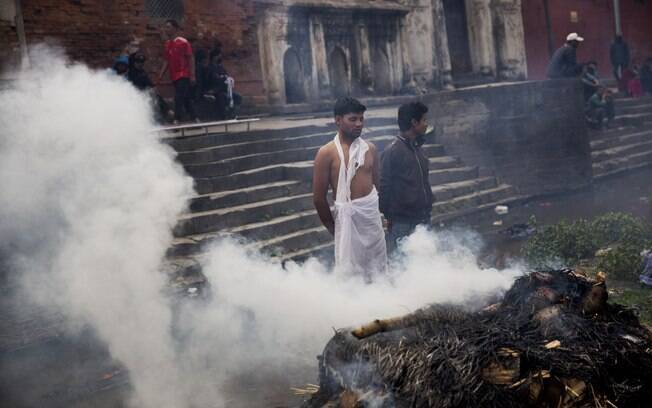 Pessoas observam cremação em plena rua de vítima de terremoto no Nepal