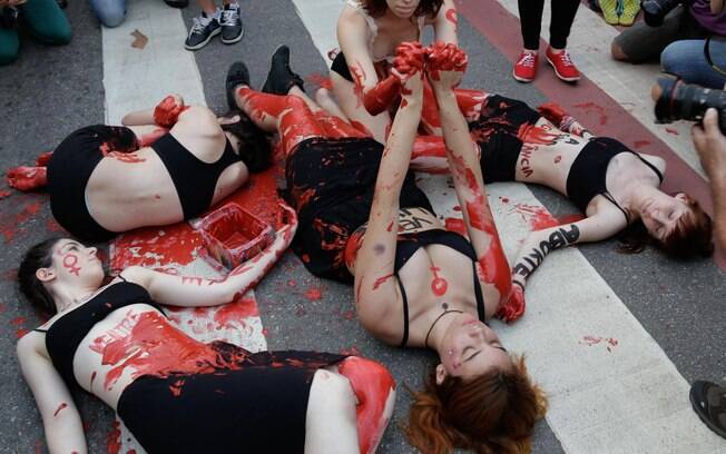 Manifestantes usam tinta vermelha para simular violência contra a mulher em ato em outubro