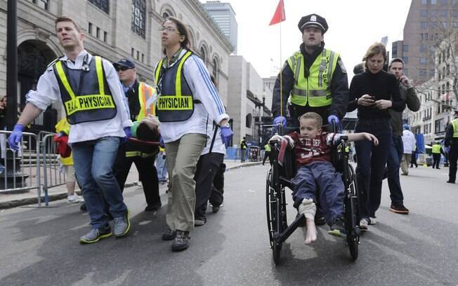 Policial leva garoto ferido de cadeira de rodas após explosões durante a maratona de Boston, nos EUA (15/04)