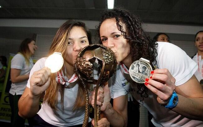 As jogadoras Deborah e Dani Piedade beijam o troféu de campeão mundial após o desembarque da seleção feminina