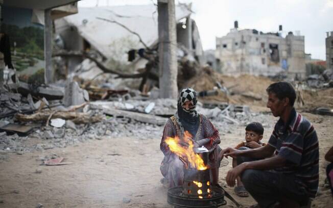 Palestinos preparam chá próximos às ruínas de sua casa em Khan Younis, no sul da Faixa de Gaza (18/08)