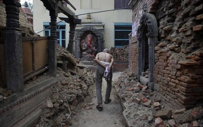 Um idoso anda pelo que restou de templo após fim do período de luto pela morte de um membro de sua família em Bhaktapur