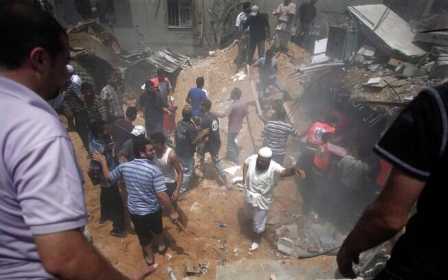Palestinos procuram por sobreviventes sob os escombros de uma casa destruída por um míssil israelense na Cidade de Gaza (21/7)
