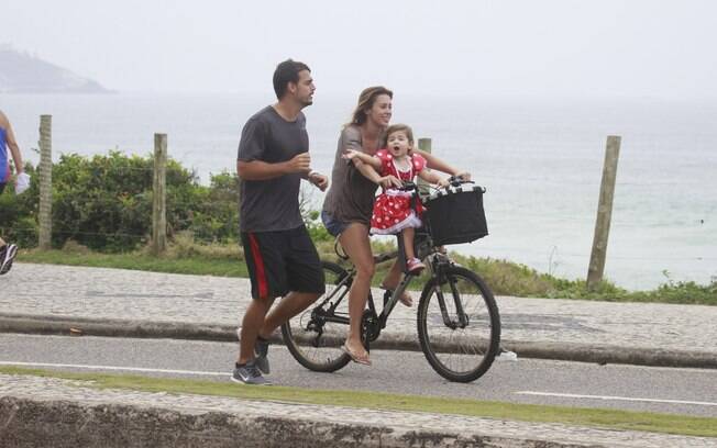 Dani Monteiro pedala com a filha, Maria,  na orla da Barra da Tijuca