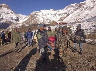 Soldados carregam vítima de avalanche antes de ser levada de helicóptero para Thorong La, Nepal (15/10)