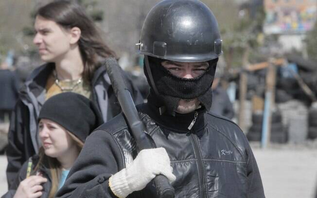 Ativista mascarado pró-Rússia guarda barricada em prédio da administração regional em Donetsk, Ucrânia (15/4)