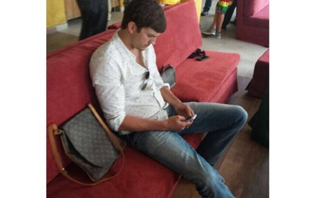 Ashton Kutcher observa o celular antes do jogo do Brasil