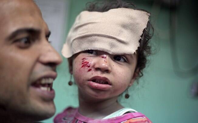 Palestino carrega menina ferida no hospital Kamal Adwan. Ela recebeu tratamento após ataque israelense a uma escola da ONU, em Gaza (30/07)
