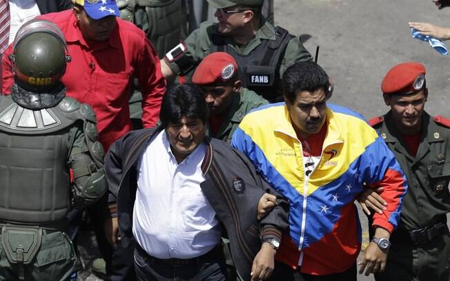 Vice-presidente da Venezuela, Nicolás Maduro (2º à D), segura braço de líder boliviano, Evo Morales, em Caracas (06/03)