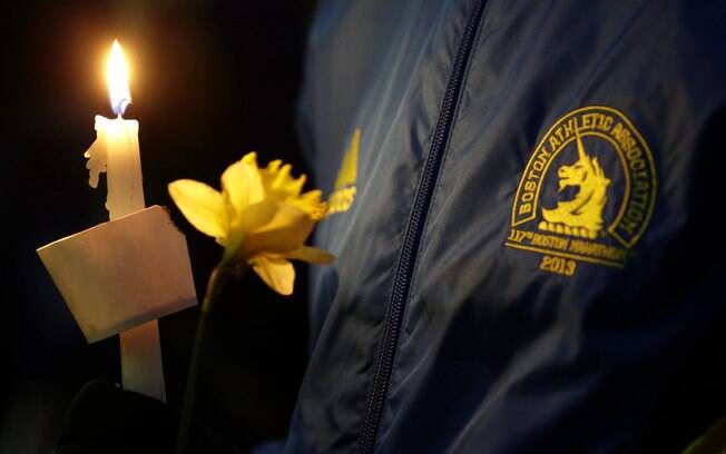 Lizzie Lee, 56, que participava de sua primeira Maratona de Boston, segura vela e flor durante vigília por vítimas de ataque (16/04)