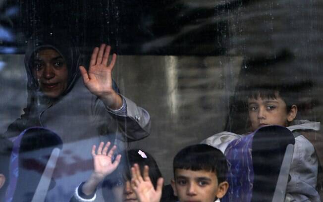 Família síria acena a parentes após entrar em ônibus em direção a aeroporto para ir à Alemanha, onde foram aceitos como asilados temporários, em Beirute, Líbano (10/10)