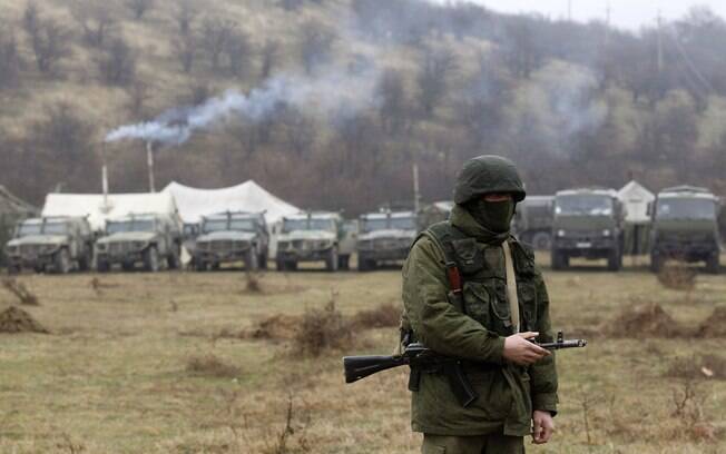 Soldado armado, provavelmente russo, anda perto de uma base militar ucraniana na aldeia de Perevalnoye (9/3)