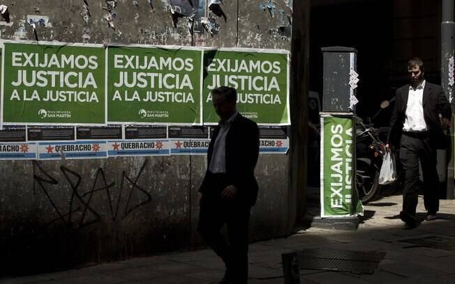 Homem passa por cartaz que faz referência a marcha organizada pelo Ministério Público Federal pedindo justiça após a morte de Alberto Nisman na Argentina (13/02)