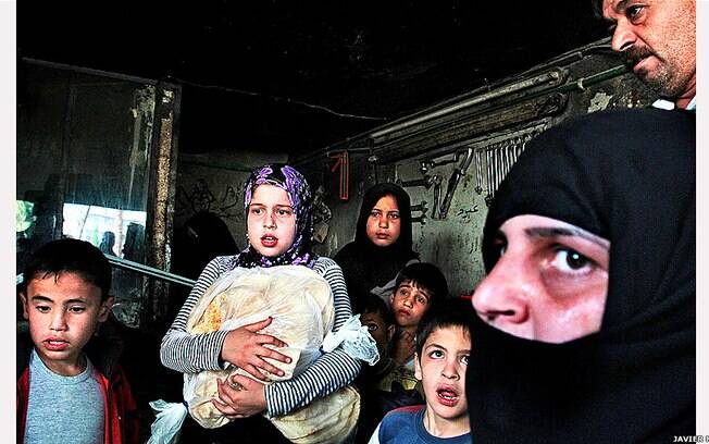 Civis em Aleppo se refugiam dentro de uma oficina, enquanto um avião de combate sobrevoa um bairro próximo a uma base do Exército Livre da Síria (foto Javier Manzano)