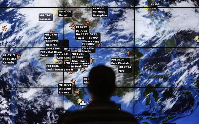 Homem observa telão mostrando diferentes decolagens no Aeroporto Internacional de Kuala Lumpur, Malásia (13/3). Foto: Reuters