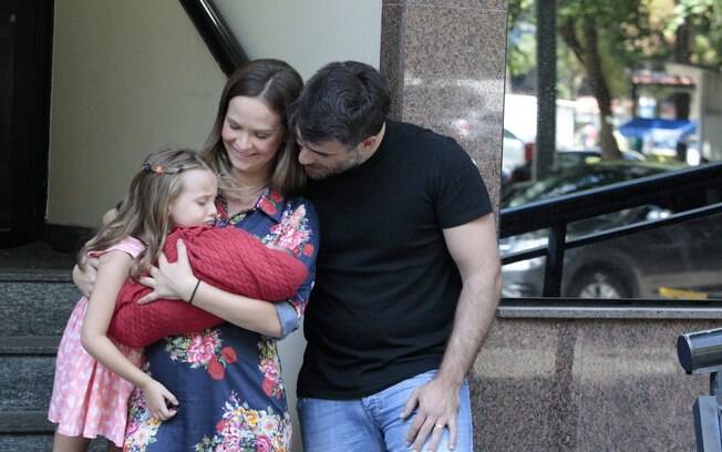 Luiza observa o irmãozinho no colo da mãe
