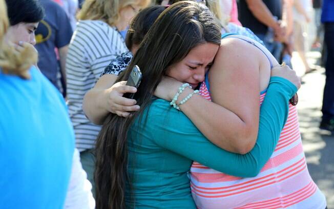 Tia e sobrinha se abraçam ao aguardar notícias sobre uma das alunas da faculdade de Oregon