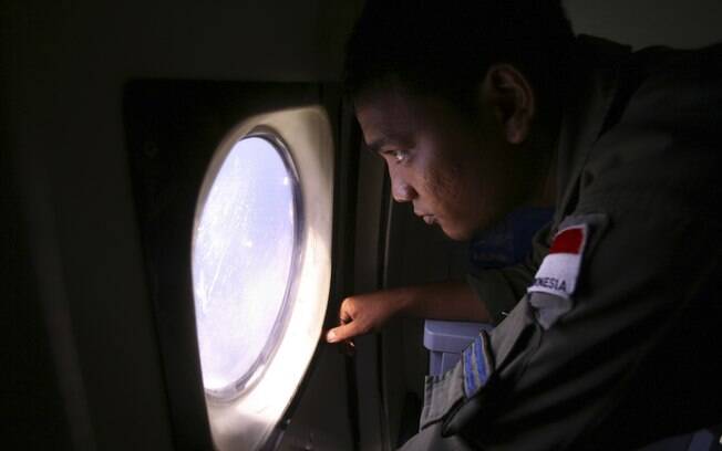 Membro da tripulação da Marinha indonésia observa águas na fronteira da Indonésia, Malásia e Tailândia durante buscas por avião (10/3). Foto: AP