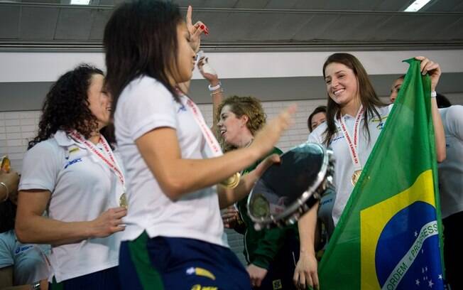 Ao lado das demais jogadoras da seleção, a armadora Duda segura a bandeira do Brasil no desembarque em São Paulo