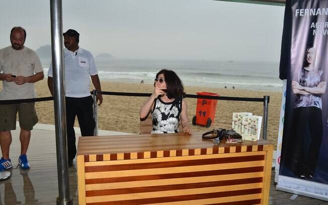 Fernanda Torres autografa livro em quiosque na praia em dia de chuva
