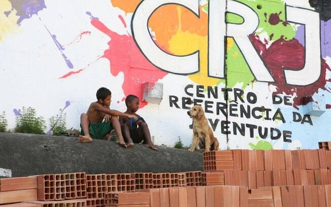 Crianças brincam com cachorro na favela