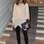 A socialite Olivia Palermo usou wet legging preta com blusa solta off-white e ankle boots pretas. A pulseira, a bolsa azul Dior e o colar deixam o look mais glamuroso. Foto: Getty Images