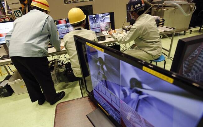 Trabalhadores assistem a monitor que mostra imagens ao vivo transmitidas a partir de um robô controlado por controle remoto no Japão (5/02)