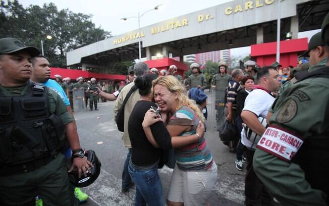 Venezuelanas se abraçam e choram do lado de fora do hospital militar onde Chávez estava internado (05/03)