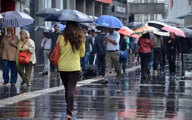 Pedestres se protegem da chuva e do frio na Avenida Paulista, em São Paulo, nesta terça-feira