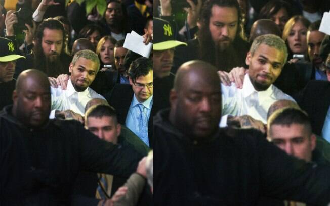 Chris Brown escoltado por seguranças na segunda-feira (28), depois de sair da delegacia onde estava detido após agredir um homem