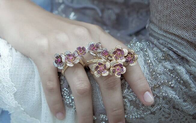 Dois anéis de dois dedos também podem ser usados juntos, como nessa composição da Goldesign. As peças de ouro 18k têm rubis e diamantes