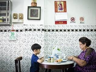 Mulher e seu neto tomam um tradicional café da manhã em Cingapura, com ovos moles, torrada e café no kopitiam Chin Mee Chin Confectionery