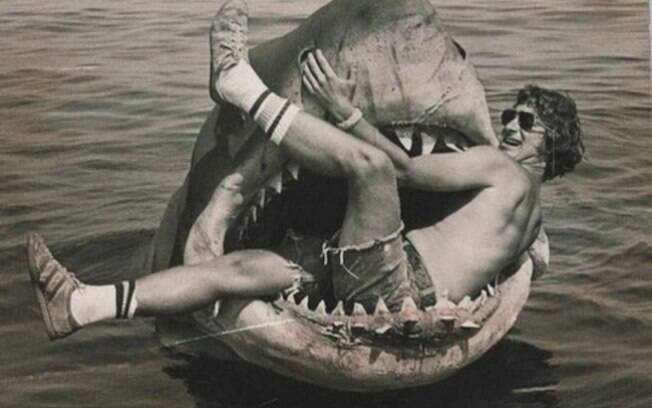 Steven Spielberg sentado no tubarão mecânico usado no filme Tubarão.