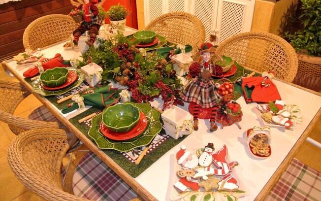 A mesa em verde e vermelho tem itens decorativos típicos de Natal e uma bonita louça