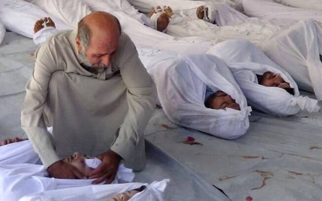 Imagem fornecida pelo Gabinete de Mídia de Douma mostra sírio ao lado de corpos de vítimas mortas por suposto ataque químico