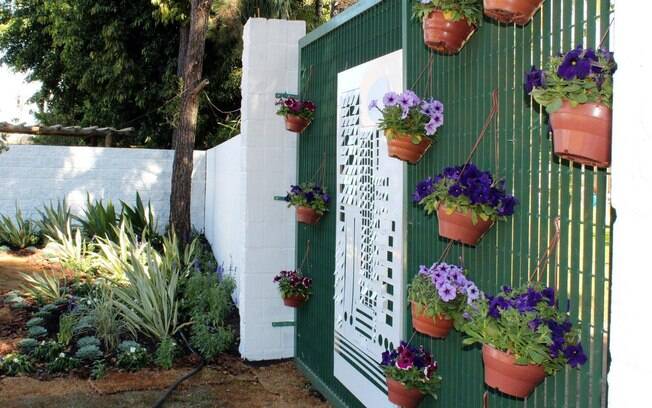 E que tal transformar o portão em um jardim? Pendure os vasos nas grades e cuide da manutenção. Projeto da Expoflora