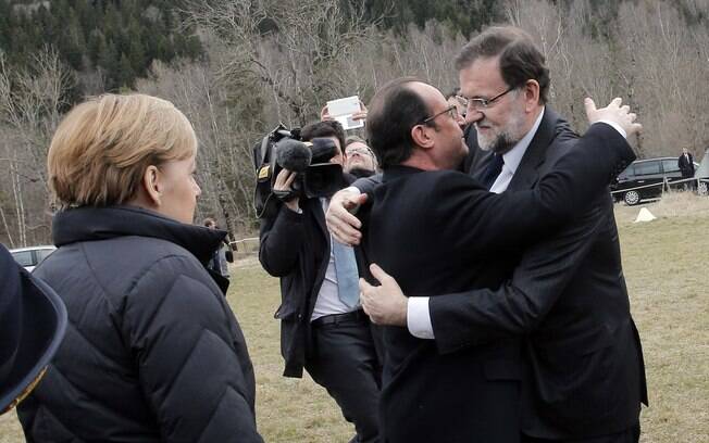 Mariano Rajoy (à direita) é observado por Merkel enquanto cumprimenta François Hollande
