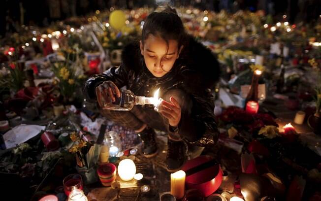 Criança acende velas em homenagem a vítimas de atentados de Bruxelas, na Bélgica
