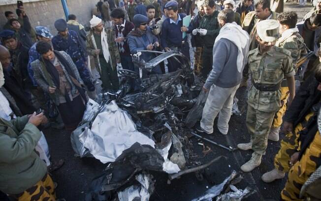 Investigadores de polícia do Iêmen perto dos destroços no local onde um carro bomba foi detonado perto de delegacia em Sanaa