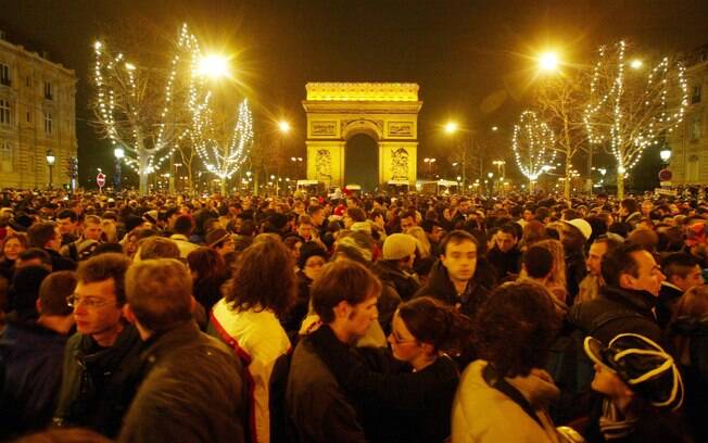 Foliões se reúnem na avenida Champs Elysées para comemorar a virada, mesmo sem música e fogos de artifício
