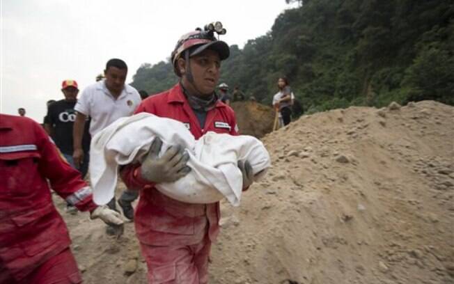 Bombeiro carrega corpo de criança que morreu em tragédia causada pela chuva na Guatemala