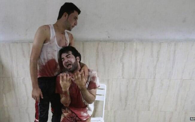 Homem com roupas manchadas pelo sangue é consolado em hospital em Khan Younis: cerca de 1.900 palestinos morreram em Gaza (9/08)
