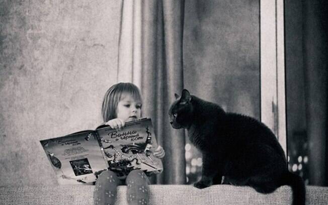 Menina contando uma história pro seu lindo gato preto.